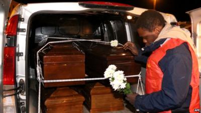 Man with flowers by van containing coffins