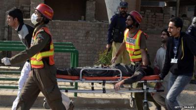 Pakistani volunteers move an injured worshipper near a Shiite Muslim mosque after an attack there by Taliban militants in Peshawar on 13 February 2015