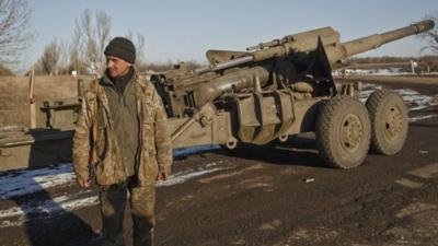 An Ukrainian serviceman stands next to an artillery piece outside Artemivsk, Ukraine, after pulling out of Debaltseve