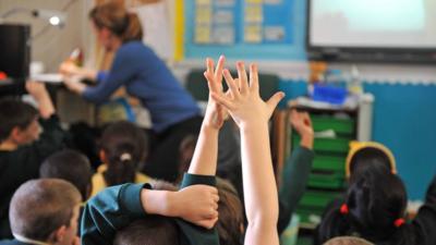 School pupils raise their hands in the classroom