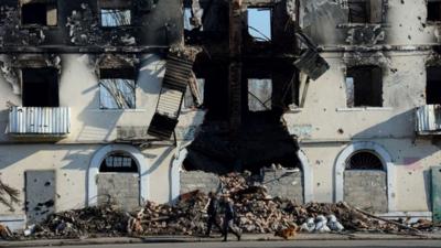 People walk past a building damaged in fighting in Vuhlehirsk, just south of Debaltseve