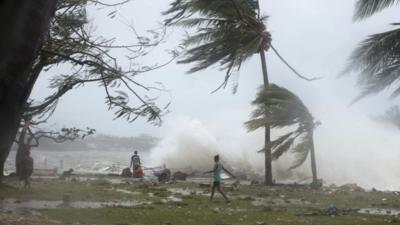 In this image provided by UNICEF Pacific people walk along the shore where debris is scattered in Port Vila, Vanuatu, Saturday, March 14, 2015