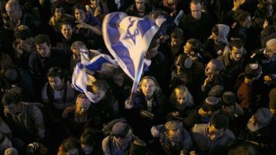 Woman in crowd waving an Israeli flag