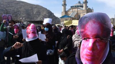 Afghan members of the Solidarity Party of Afghanistan wearing masks bearing an impression of Farkhunda's bloodied face protest against the attack in Kabul