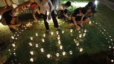 Members of the public light candles to form the acronym "R. I. P." at a local community club in Singapore