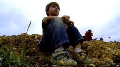 5-year-old Wylie from Dallas sitting on a mound of earth at the site where he uncovered a dinosaur fossil