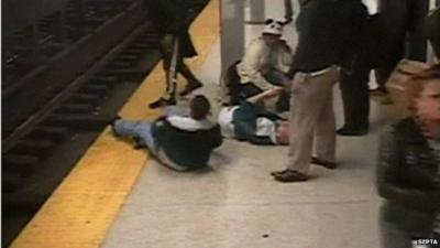 Alfred McNamee lying on ground (r) after being rescued from subway tracks by Charles Collins seen lying on ground (l)