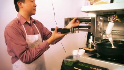 Timothy Chen loads ingredients into the robot chef device "Cooki"