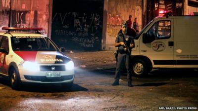 Policemen stand guard near the Corinthians' fans club in Vila dos Remedios after shooting in which eight people were killed