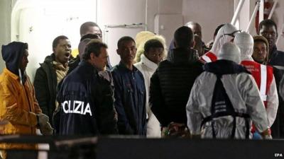 Italian authorities guide migrants who survived ship sinking at Catania's port in Sicily