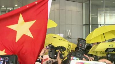 Protestors, some carrying yellow umbrellas, some with a Chinese flag