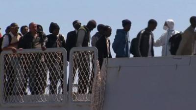 Migrants walking off a boat