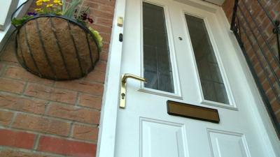 The front door of a house and hanging basket