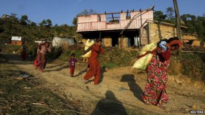 Earthquake victims carry relief materials on their backs at a village in Sindhupalchowk