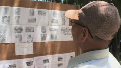 Man looks at missing persons board