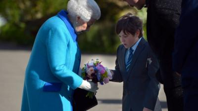 Queen being handed flowers by schoolboy