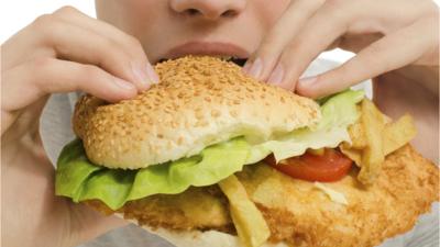 Burger and fries being eaten by a young person