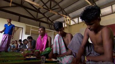 Bangladeshi migrants eating a meal in a camp for migrants in Indonesia