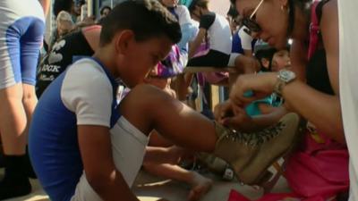 A child gets their laces tied