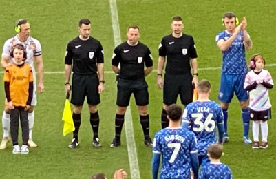 Players and children wearing ear defenders as teams come onto a football pitch