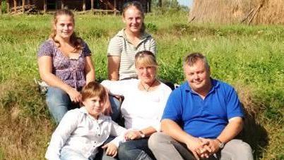 The Duncan Ridgley family, showing three children, a woman and a man sitting on grass. They are all looking straight at the camera. 