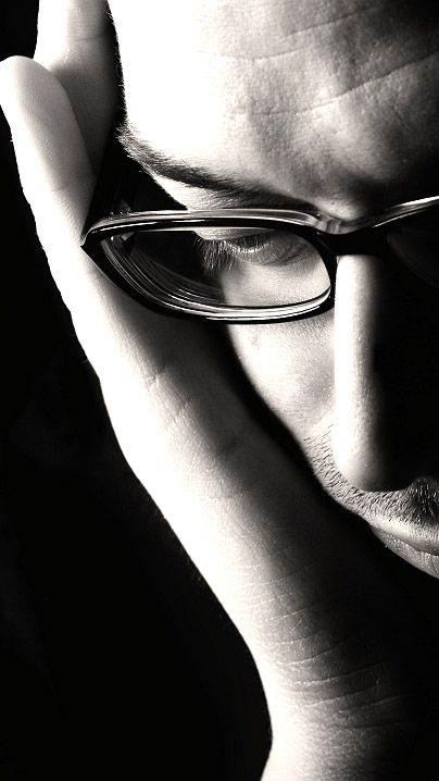 Man wearing glasses with his head in his hands