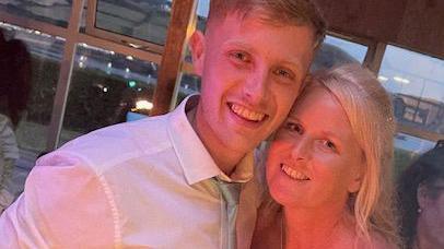 Ethan and Jo posing for a photograph together at a function. He is wearing a white shirt and light green tie.