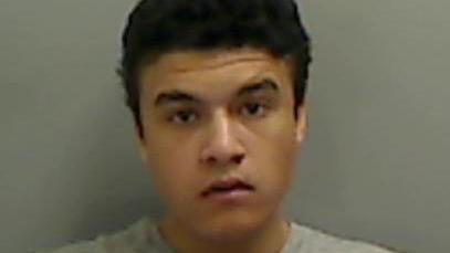 Mugshot of Cartel Collinson, who has short black hair and thick black eyebrows. He is wearing a grey jumper.