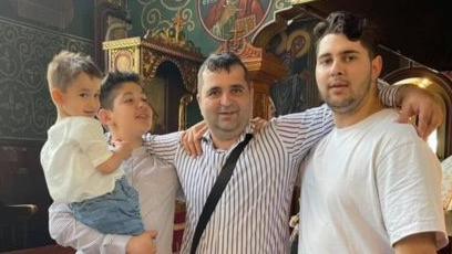 Mr Genov, right, wears a right t-shirt. He is standing with his father, who wears a white striped shirt and his two younger brothers, the older of which is holding the youngest. 