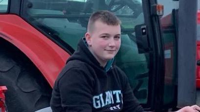 A smiling Isaac Roxborough sitting on a tractor