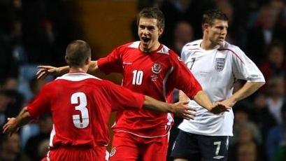 Aaron Ramsey celebrates with a Wales Under-21 team-mate as James Milner stands with hands on hips in the background