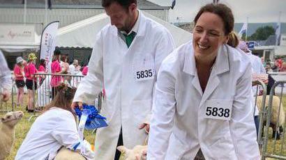 Menyw mewn cot wen yn sefyll mewn pen dafad 