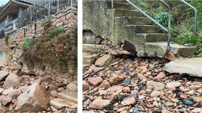 Holes can be seen in a sea wall and the bottom of the concrete steps appear to be crumbling and damaged.