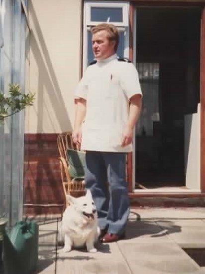 A young Jimmy Cooper at home in his nursing uniform, with a Corgi dog beside him