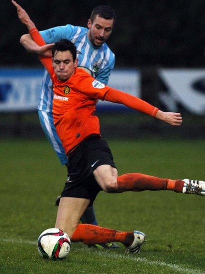 Mark Surgenor of Carrick Rangers gets the ball away under pressure from Warrenpoint Town opponent Stephen Murray during the 1-1 draw at Milltown