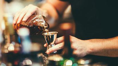 A stock image showing a man preparing an alcoholic drink at a bar. 