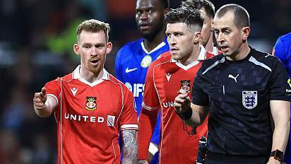 Lewis O'Brien of Wrexham speaks to Referee Peter Bankes as a VAR review takes place