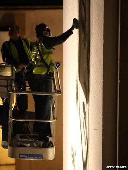 Two graffiti artists spray paint the wall of a high rise building in Bristol.