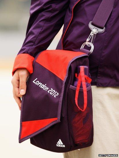 A volunteer for the London 2012 Olympics wearing their new uniform with bag and umbrella.