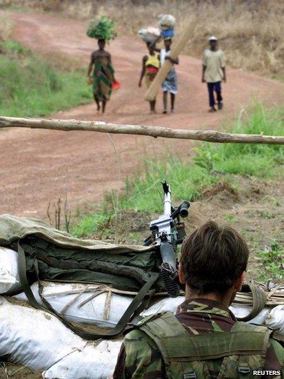 An unidentified British paratrooper watches villagers approaching his position in Lungi Loi 30 km east of Lungi airport, 18 May 2000