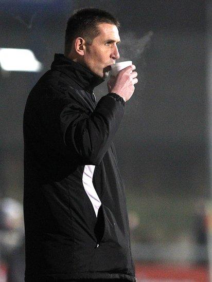 Crusaders manager Stephen Baxter stays warm with a cup of tea on the sideline