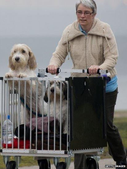 An owner arrives with her dogs on the second day of the Crufts dog show on Friday