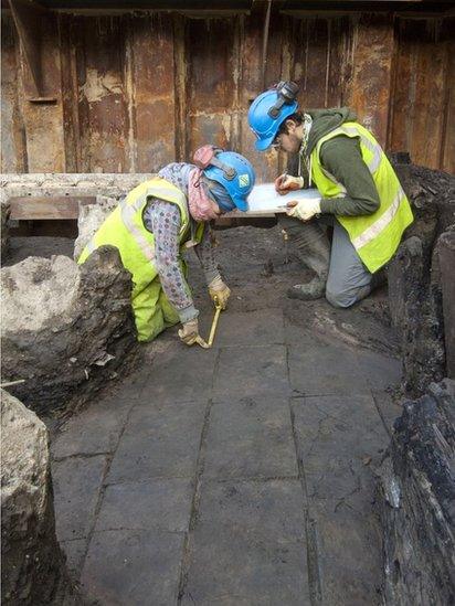 Two archaeologists measuring flagstones