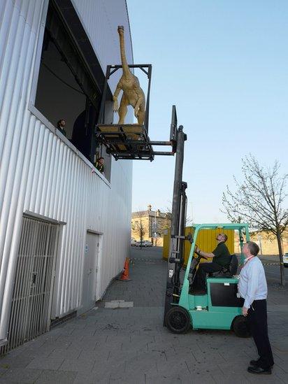 Dinosaur model being lifted into a specially-created entrance.