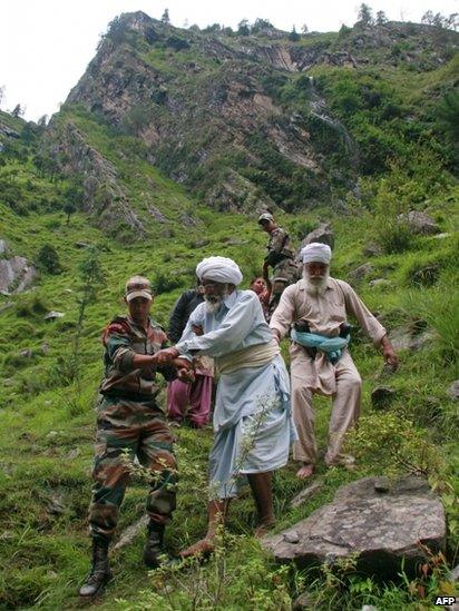 Indian army officials help travellers and villagers down a steep slope after they were stranded by the rising floodwaters of the River Alaknanda near Govindghat, Chamoli District in the northern Indian state of Uttarakhand on June 18,