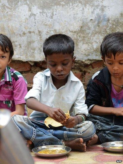 Indian schoolchildren at a school in Ahmedabad eat their free mid-day meal on 17 July 2013