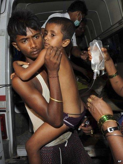 An Indian man carries a boy on a drip out of an ambulance in Patna on 17 July 2013.