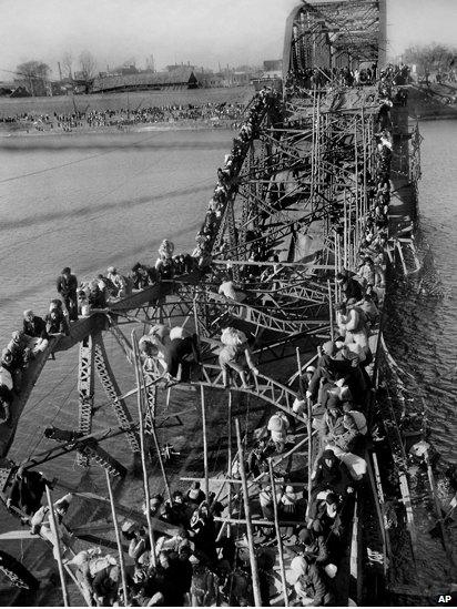 Residents from Pyongyang, North Korea, and refugees from other areas crawl over girders of the city's bridge as they flee south to escape the advance of Chinese soldiers