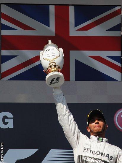 Lewis Hamilton lifts the winners' trophy