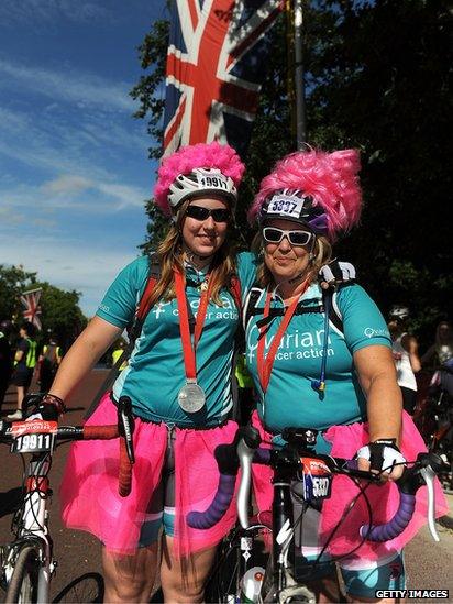 Cyclists in pink wigs pose after finish line